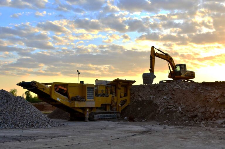 Mobile stone crusher and excavator crushing rocks in a quarry