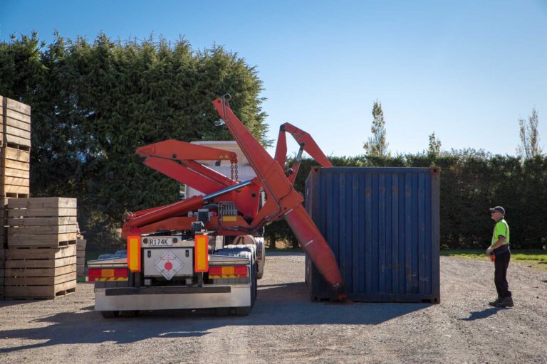 A truck driver delivers and unloads a container on a farm